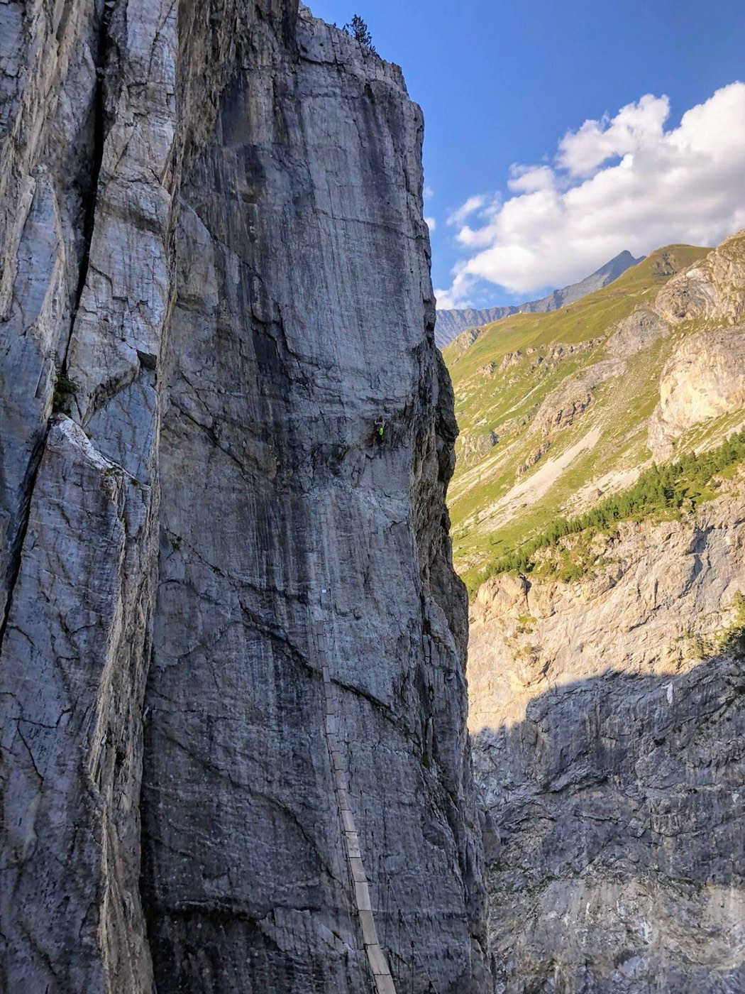 Via ferrata tracée dans une haute paroi rocheuse au-dessus d’une vallée