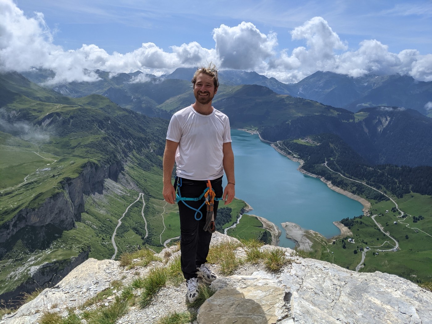 Portrait en équipement de via ferrata devant un lac de montagne